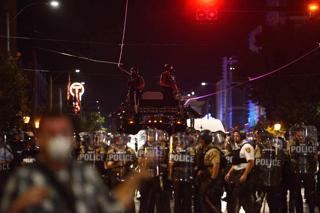 Riot police monitor the several remaining protestors on Delmar street